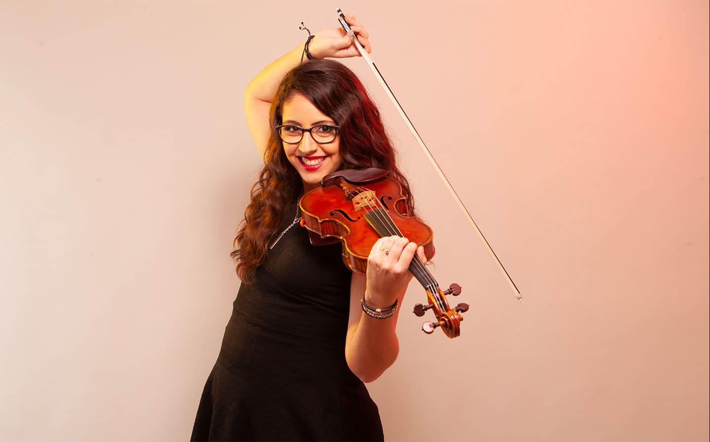 Daniela Padr&#243;n wearing a black dress smiling with a violin.